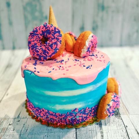 a blue and pink cake with sprinkled donuts on top