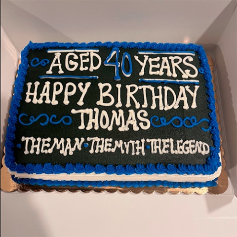 A black and blue sheet cake that says Aged 40 Years Happy Birthday Thomas, The man, the Myth, the Legend