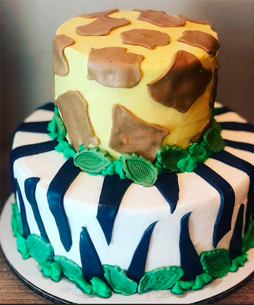 a 2 tiered cake with a cheeta and zebra print design and green leaves