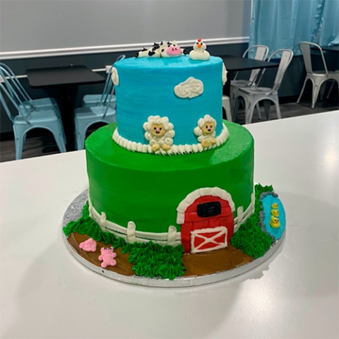 A two tiered barn house inspired cake with farm animals on top