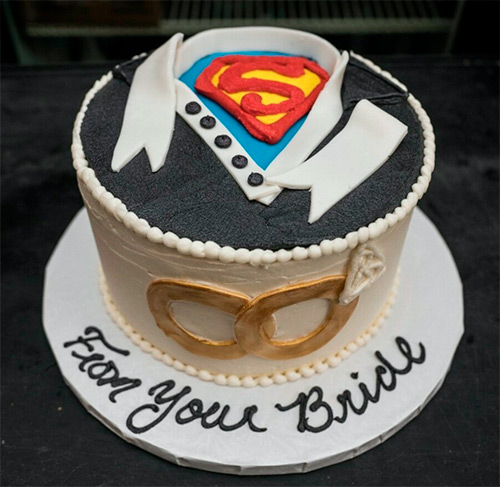 a round Superman themed cake that says From your Bride on the cake tray
