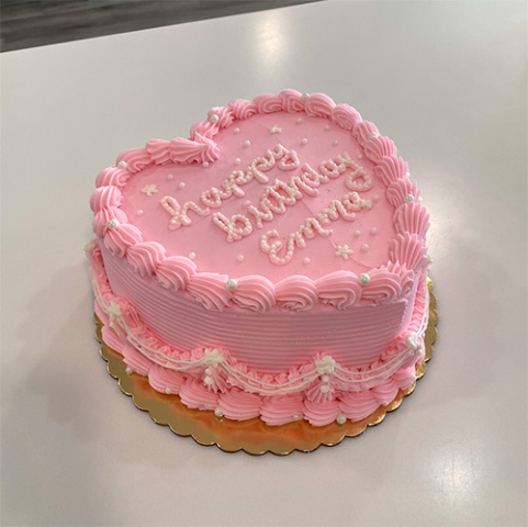 a pink heart shaped cake that says happy birthday emma in sugar pearls