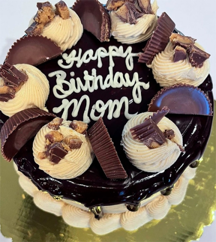 a round reeses peanut butter cup flavored cake with the words Happy Birthday Mom written on top