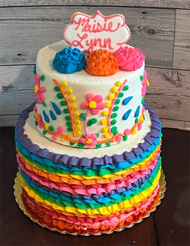 a two tiered cake with pink orange and blue colors