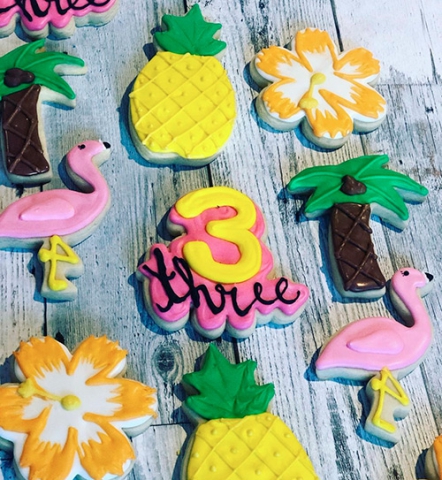Tropical themed decorated sugar cookies that include a pineapples, flamingos, palm tree and flowers